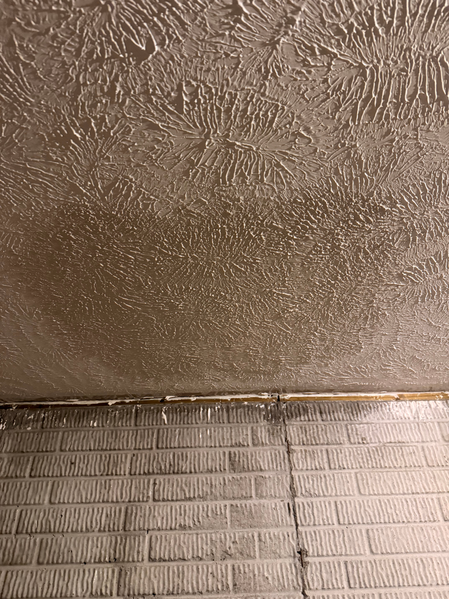 Slap-brush textured ceiling running clean to the wall line above painted brick