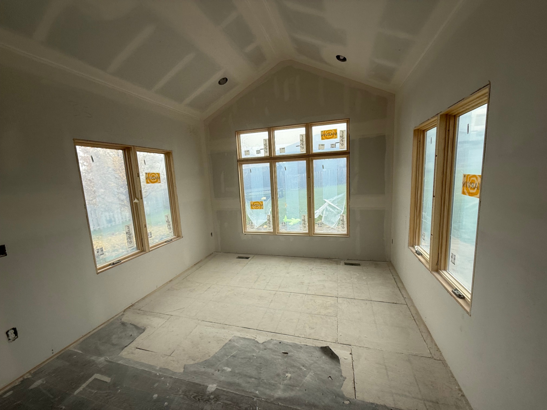 Wide view of the finished addition — paint-ready walls, vaulted ceiling, and recessed cans set