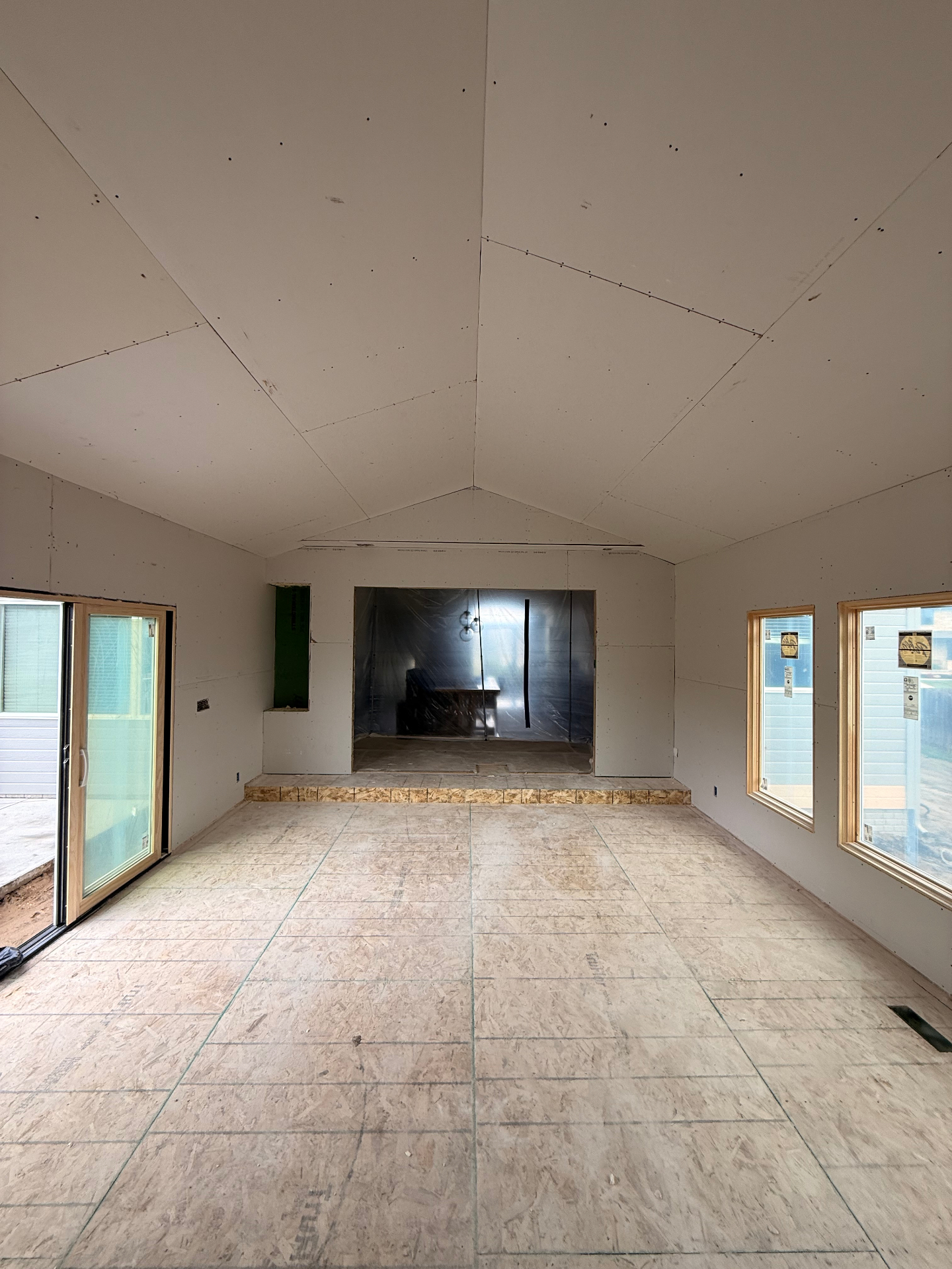 Drywall hung around the fireplace opening and step-up — clean transitions ready for finishing
