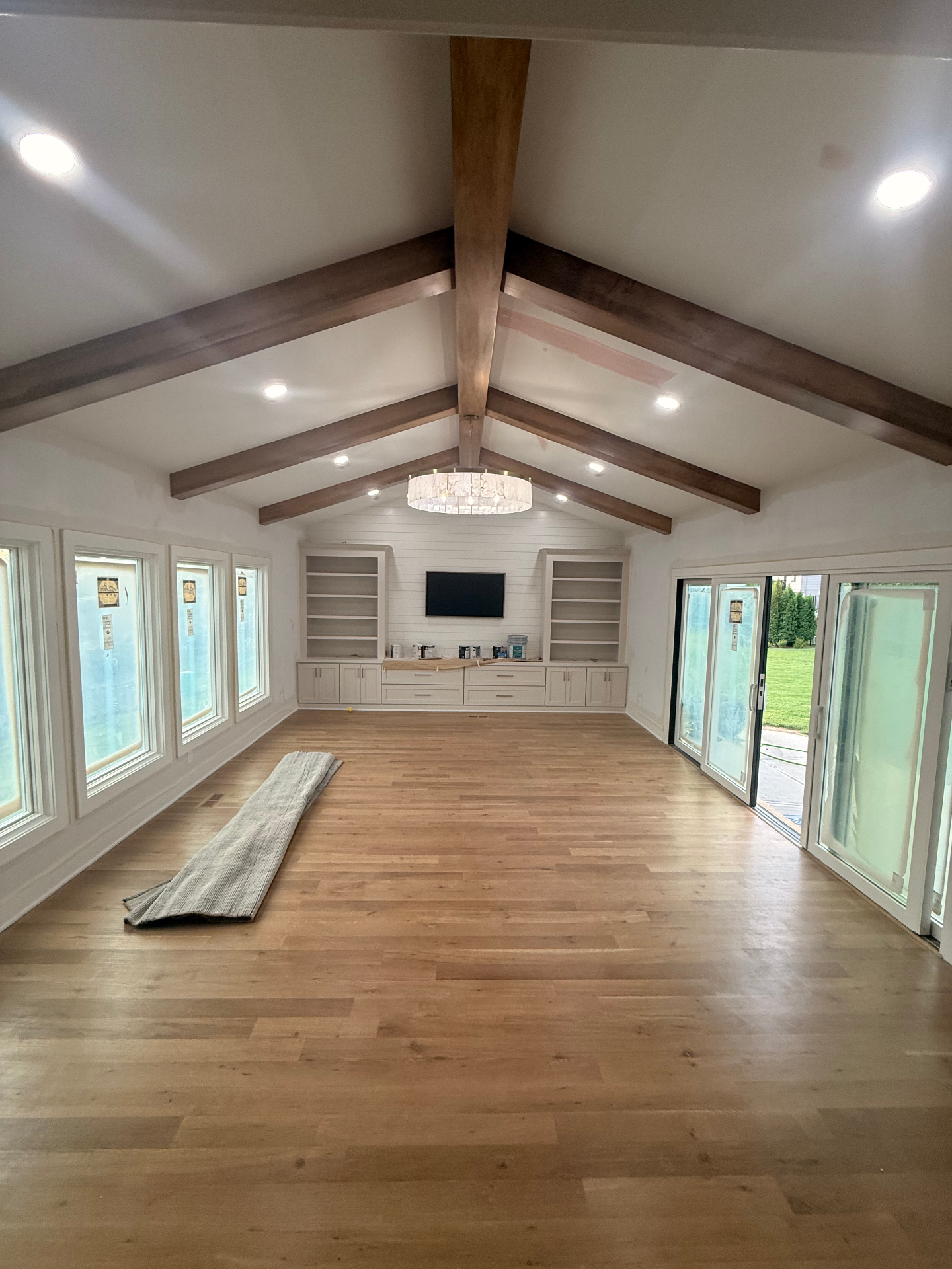 Fully finished addition — vaulted ceiling and walls painted, stained beams installed, built-ins framing the shiplap accent wall