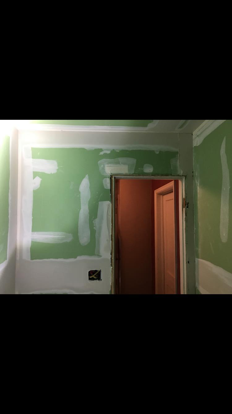 Adjoining hallway re-boarded with moisture-resistant drywall and skim-coated around the doorway transition