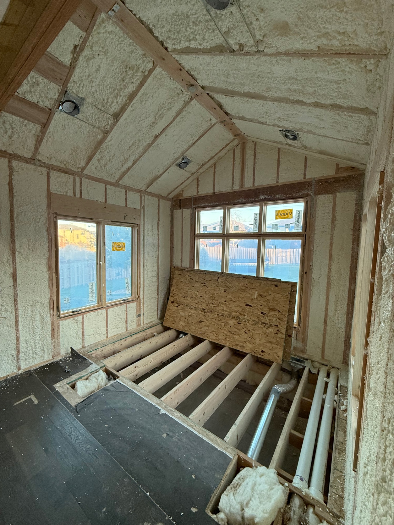 Subfloor and joists exposed with insulated walls and ceiling prepped ahead of decking and drywall