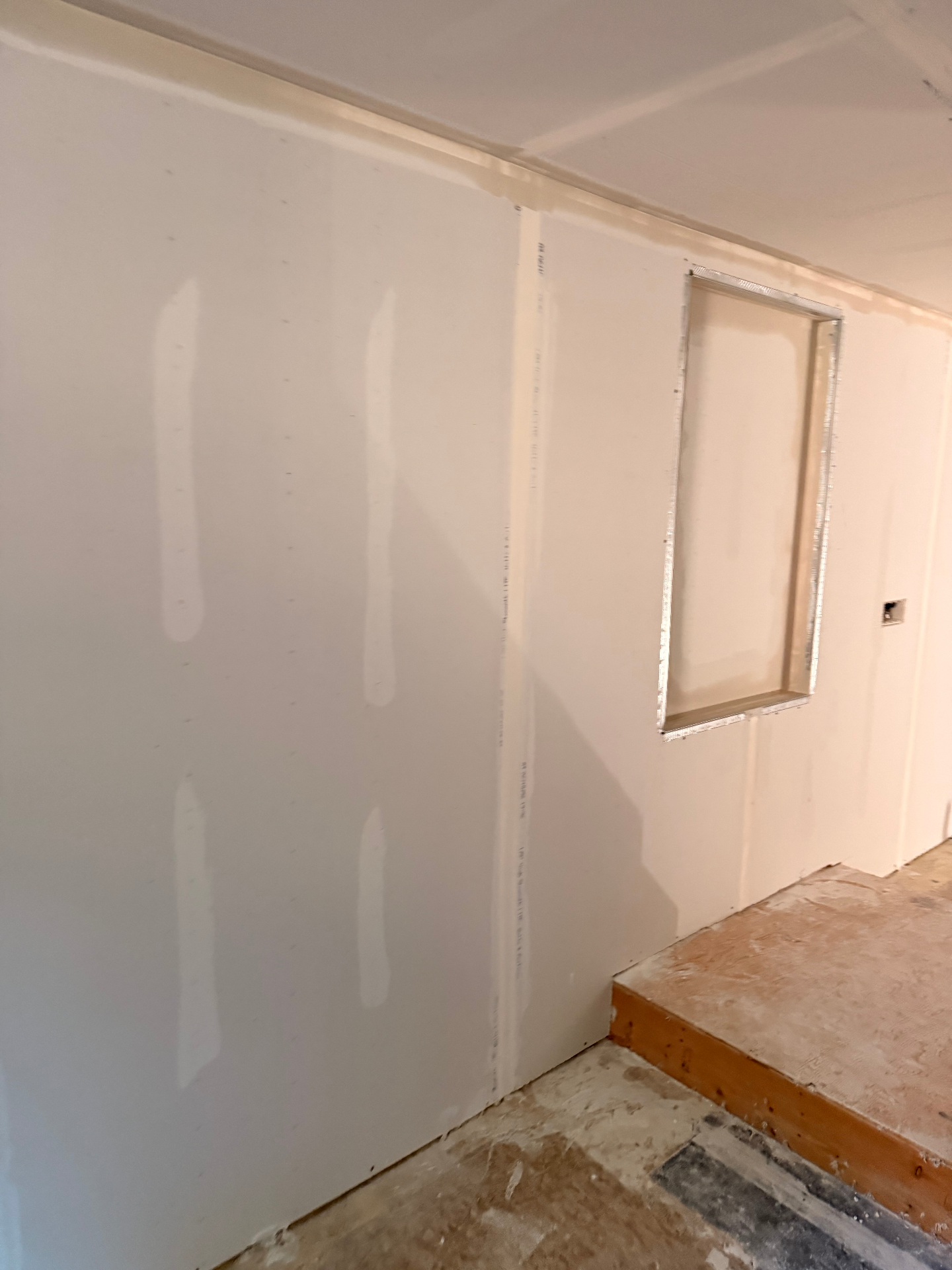 Basement wall hung with a framed niche detail — screws set and ready for tape and mud