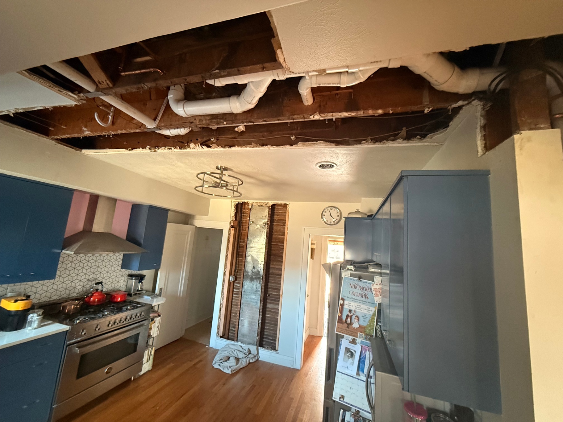 Kitchen ceiling opened up around the drain stack — old plaster removed to access the structure above