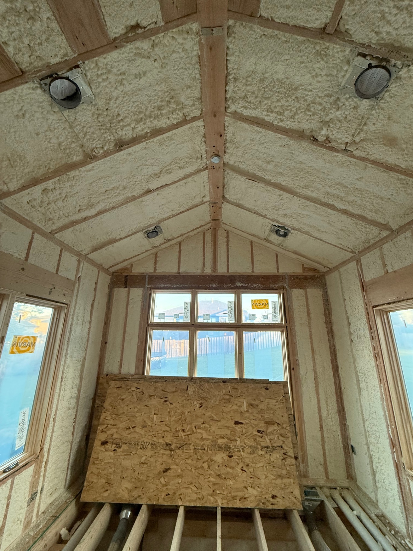 Spray-foam insulation packed between studs and rafters on the vaulted gable end before drywall