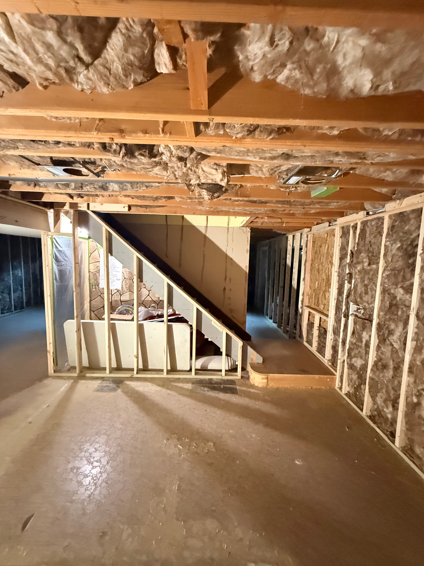 Under-stair framing and insulation exposed — drywall layout planned around the staircase and utility chase