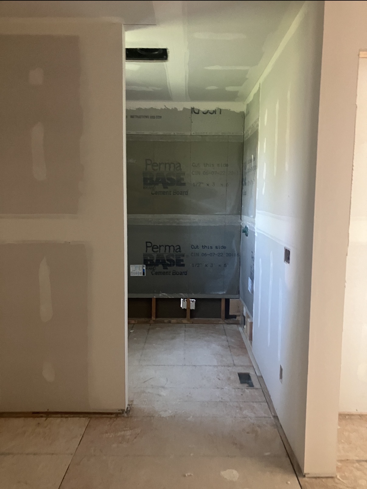 Bathroom shower walls prepped with PermaBase cement board for tile, transitioning to drywall in the rest of the room