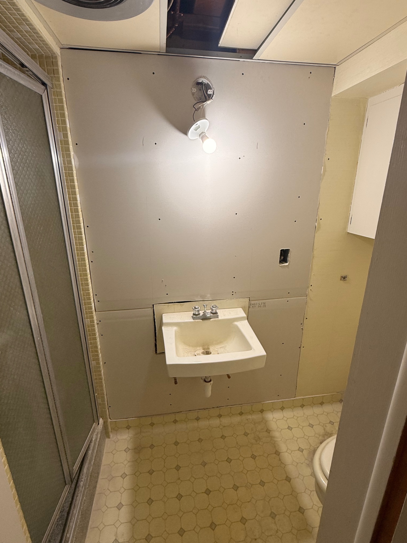 Bathroom wall rebuilt with new drywall over the original plaster substrate, ready for finishing