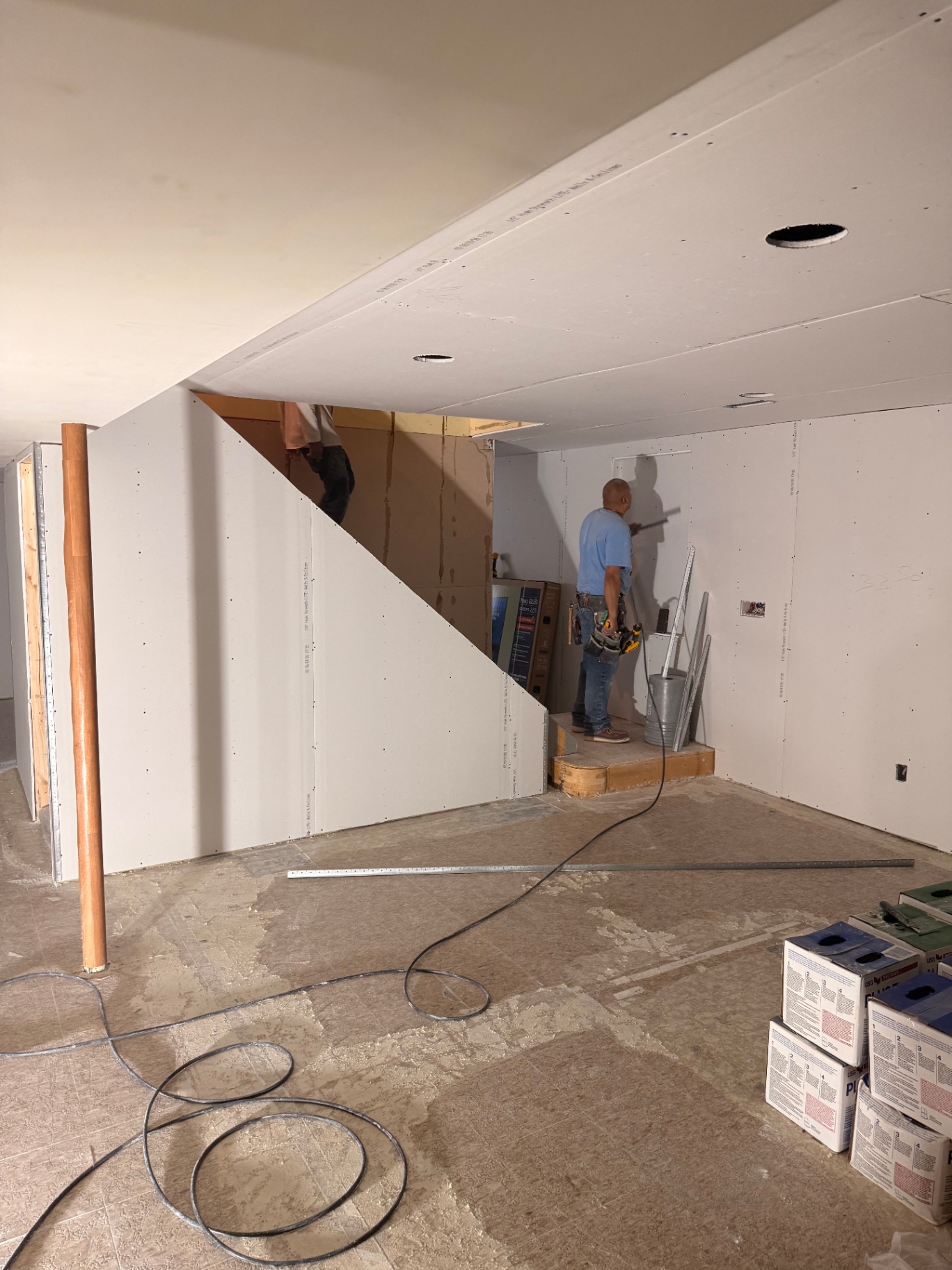 Crew hanging drywall under the stairwell and around the utility room during the basement build