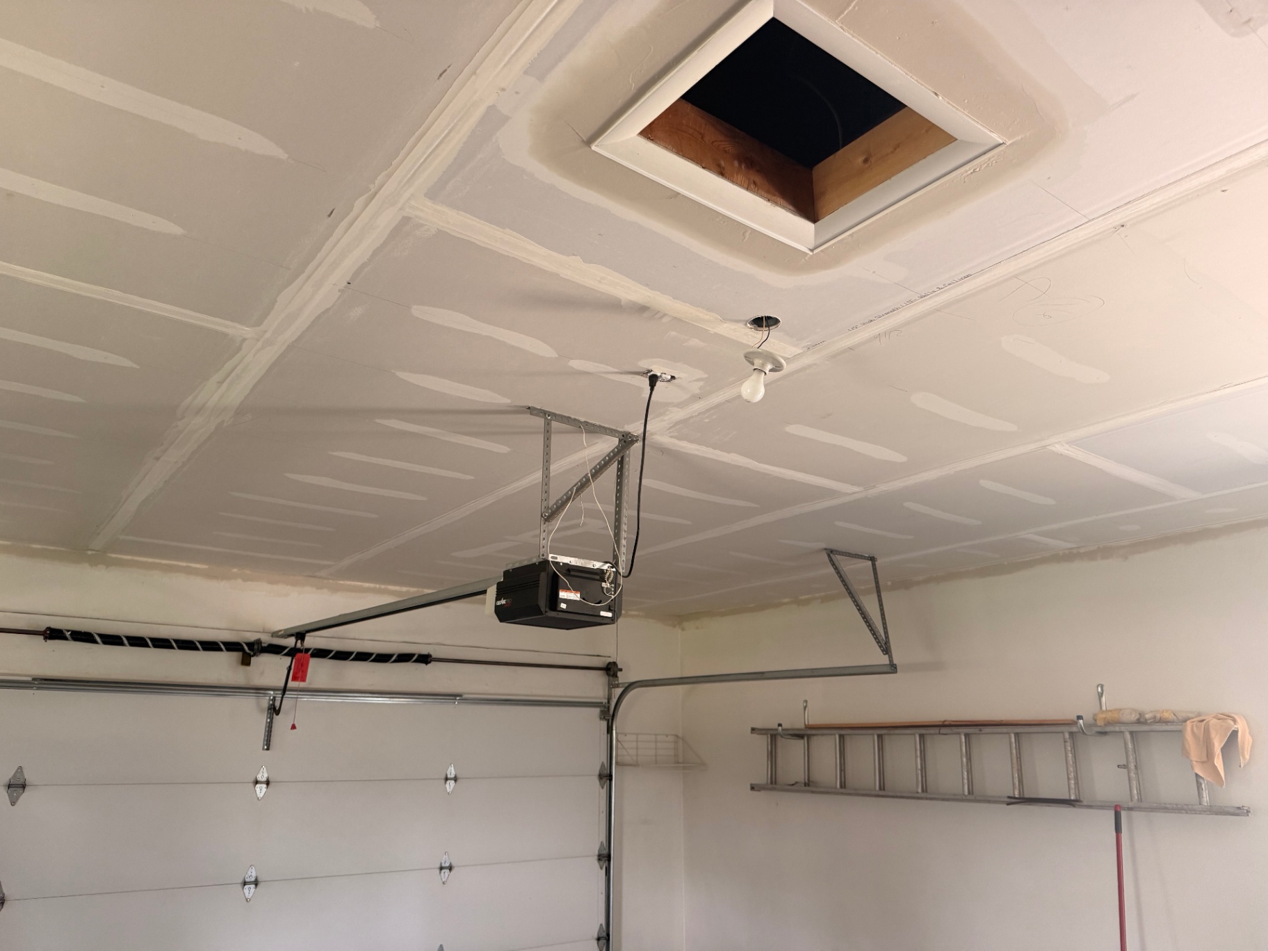 Tighter view of the new ceiling boarded around the attic chute and garage opener mount