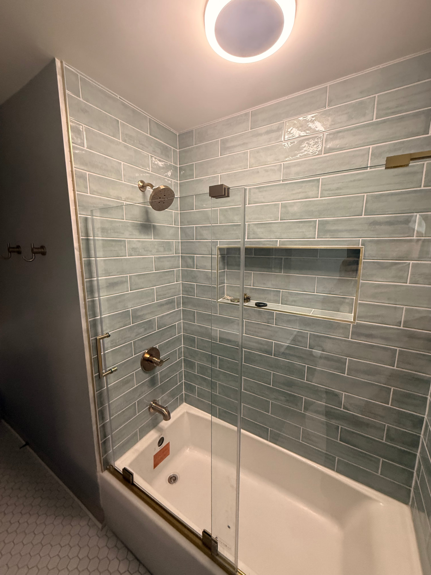 Finished tub/shower with tiled surround, recessed niche, and clean drywall transitions at the ceiling